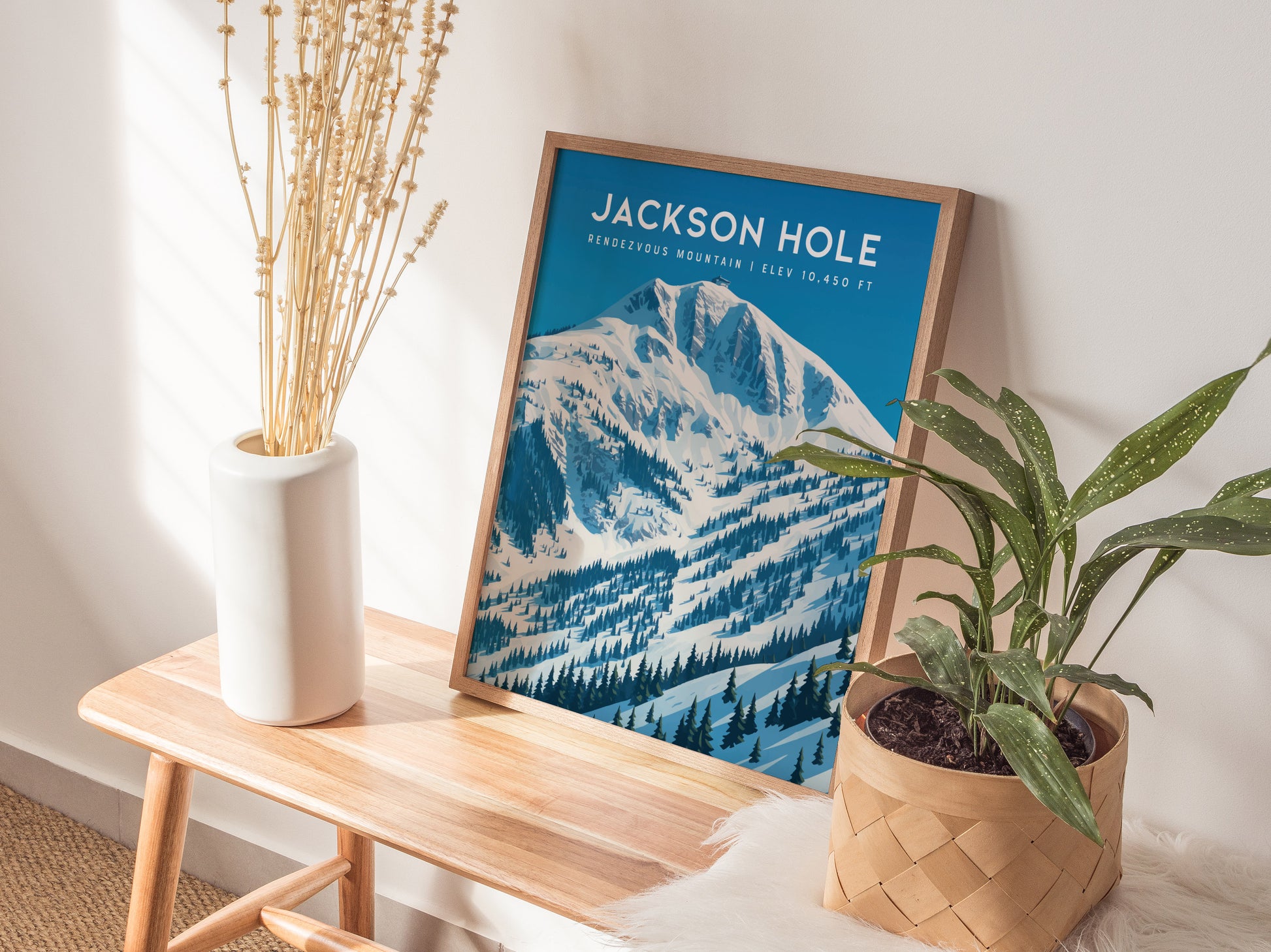 Framed Rendezvous Mountain wall art featuring a snowy landscape in Jackson Hole, with blue hues and vintage travel poster style.