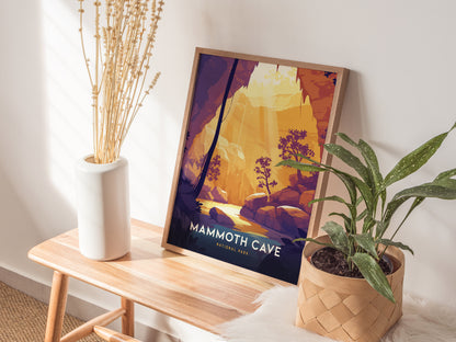 A framed Mammoth Cave National Park poster featuring a stylized cave scene is placed on a wooden bench beside a white vase with dried flowers and a potted plant.