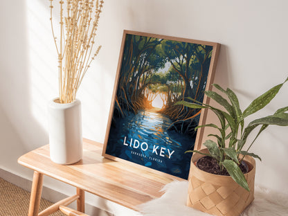 A framed poster of Lido Key mangroves rests on a wooden bench, surrounded by a potted plant and a vase of dried flowers, creating a serene ambiance.