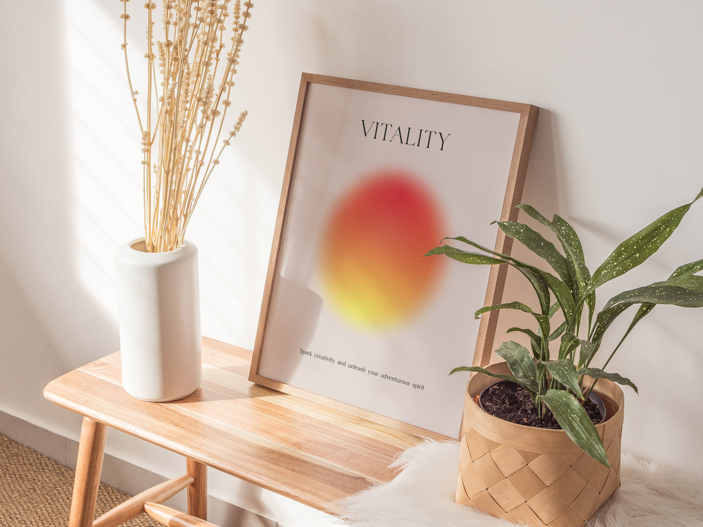 Decorative setup with a plant, vase, and framed poster on a wooden stool against a white wall.