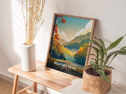 A poster of Beavers Bend State Park is displayed on a wooden bench, alongside a white vase with dried flowers and a potted green plant.