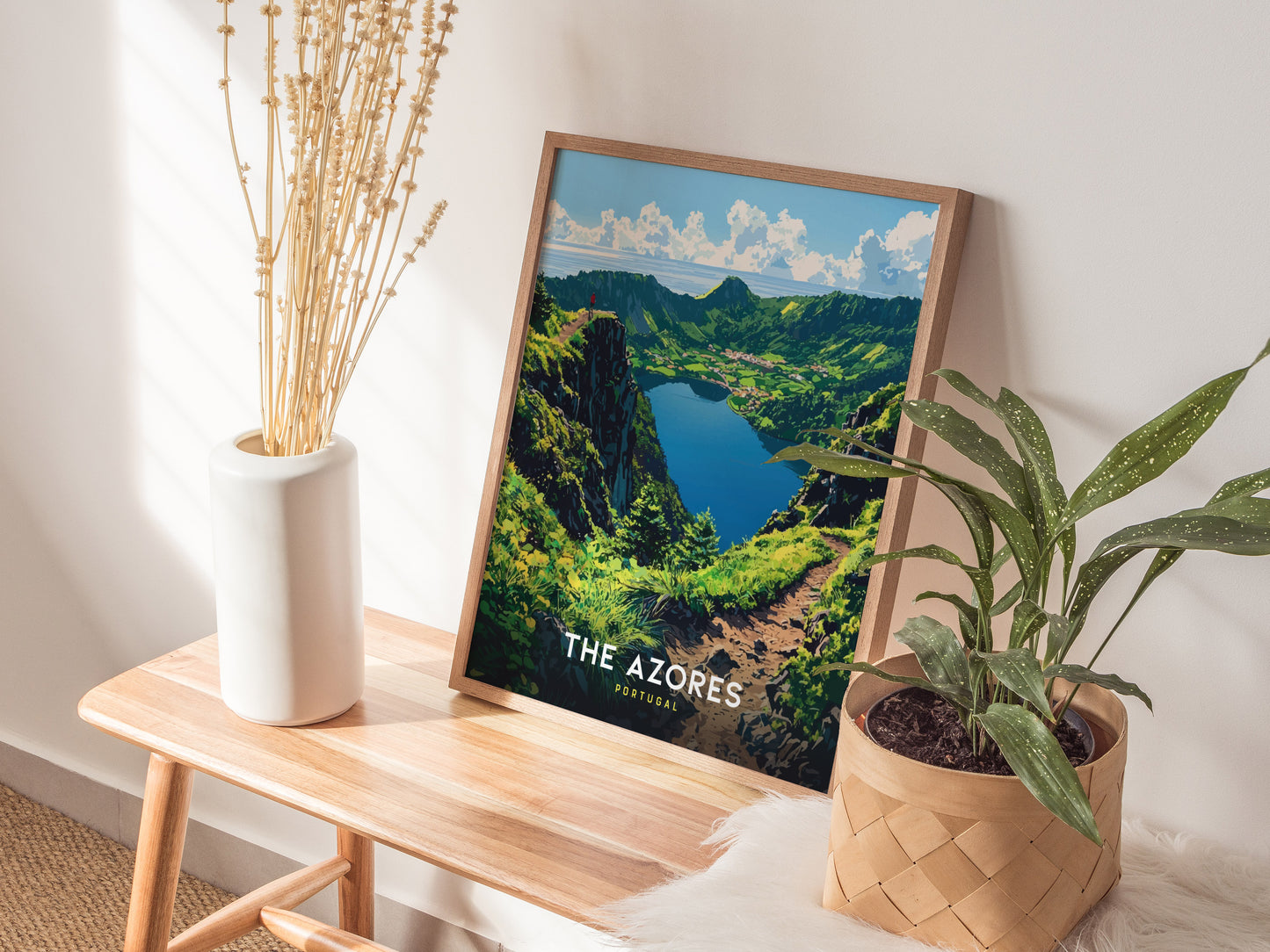 Framed poster of The Azores on a wooden table with plants and a vase.