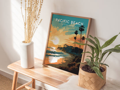 A framed Pacific Beach San Diego poster sits on a wooden bench, showcasing a vibrant sunset with palm trees and ocean waves. It is surrounded by a white vase with dried plants and a green potted plant, creating a serene coastal vibe.