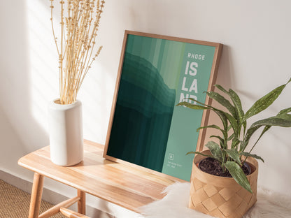 A framed abstract poster titled Rhode Island rests on a wooden bench, accompanied by a white vase with dried flowers and a potted plant, creating a modern decor setup.