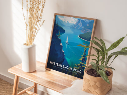 A framed poster of Western Brook Pond showing a fjord with a sailboat is placed on a wooden bench next to a white vase and a potted plant.