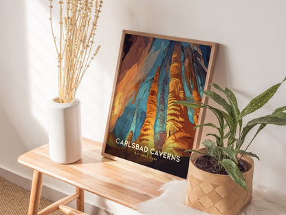 A Carlsbad Caverns National Park poster leans against a wall on a wooden bench, accompanied by a white vase with dried flowers and a potted green plant.