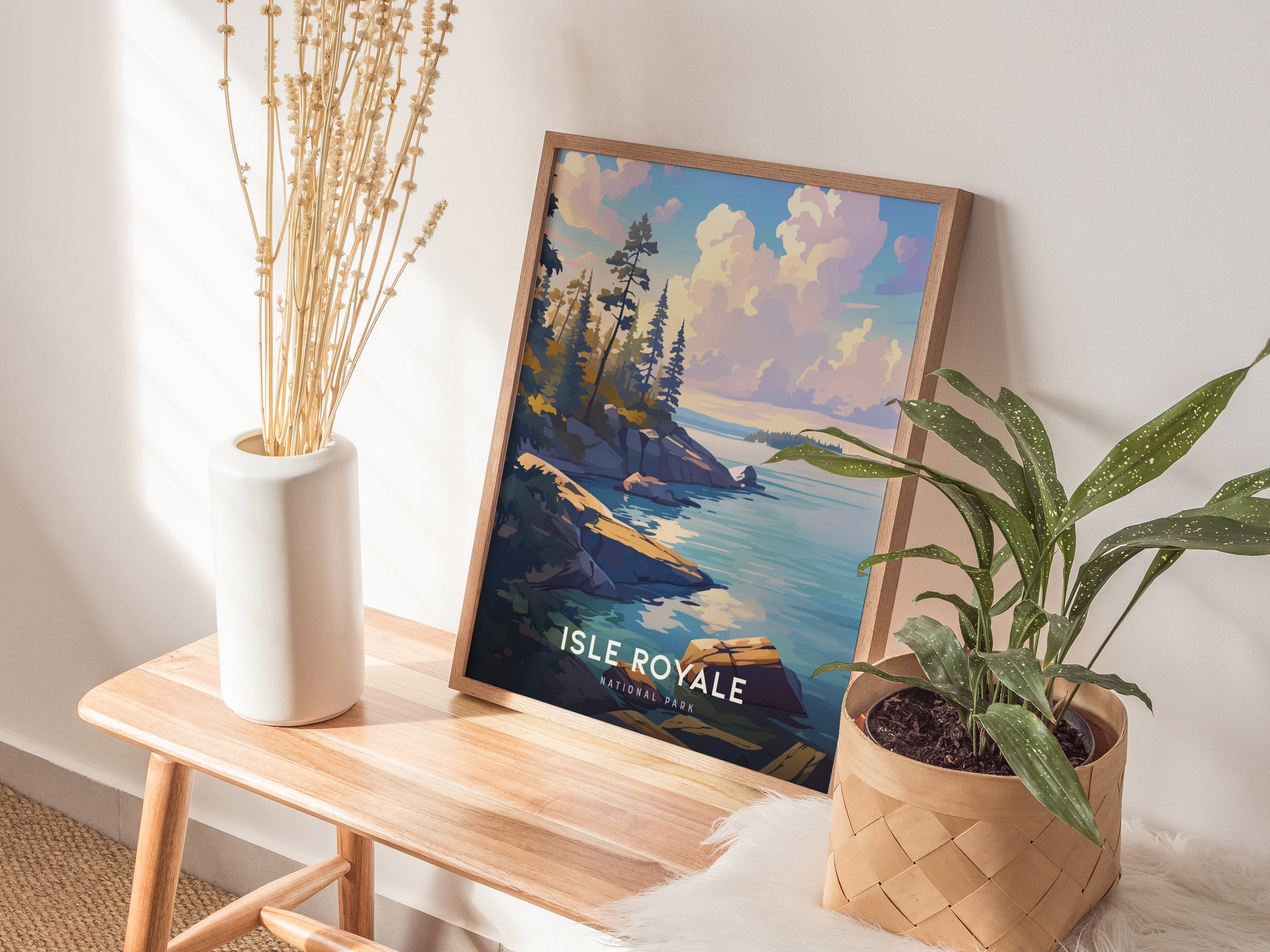 A framed Isle Royale National Park poster featuring a scenic landscape with rocky shorelines and water, leaning against a wall on a wooden bench, accompanied by plants.