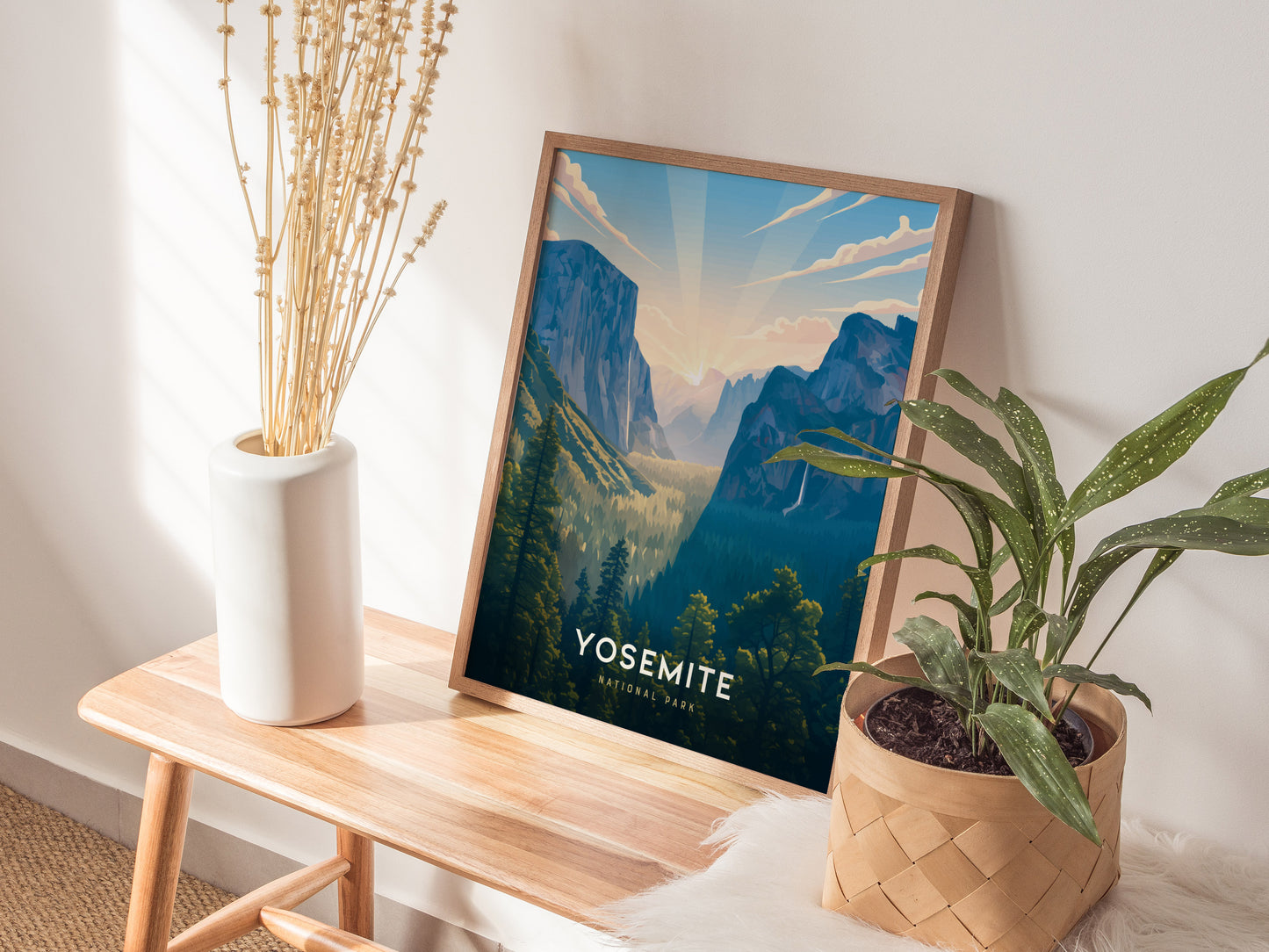 Framed Yosemite print on a wooden table with plants and a vase.