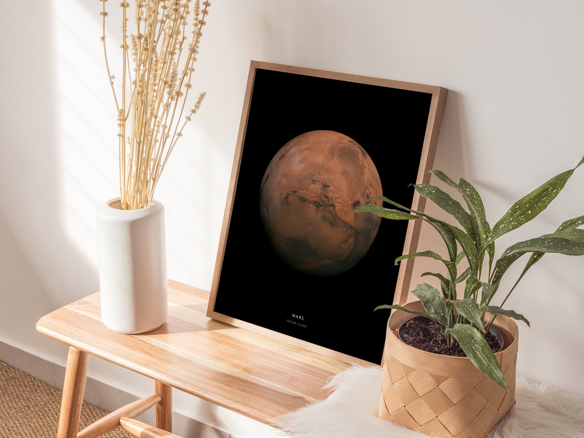 Framed poster of Mars on a wooden side table with plants and a vase.