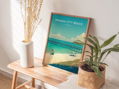 A framed Panama City Beach poster rests on a wooden bench, accompanied by a white vase with dried flowers and a potted green plant, under natural sunlight.