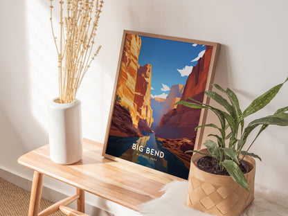 A framed poster of Big Bend National Park leans against a wall, alongside a white vase with dried plants and a leafy green plant in a woven basket.