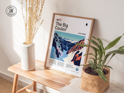 A framed poster of The Big Couloir ski run at Big Sky, Montana, leans against a wall on a wooden bench, next to a vase of dried flowers and a.