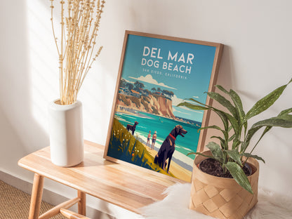 A framed Del Mar Dog Beach poster sits on a wooden bench, surrounded by a white vase with dried flowers and a green potted plant, evoking a coastal vibe.