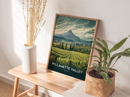 A framed Willamette Valley poster featuring lush vineyards and a mountain backdrop is displayed on a wooden bench, flanked by a vase of dried flowers and a potted plant.