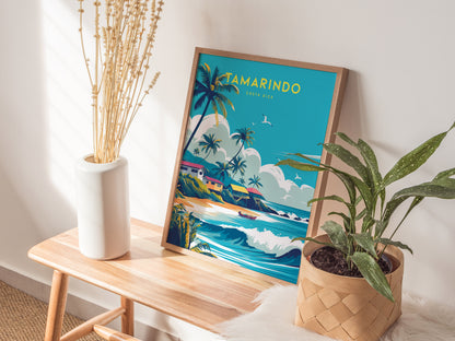 A vibrant Tamarindo, Costa Rica poster leans against a wall on a wooden table, accompanied by a white vase with dried plants and a potted green plant.
