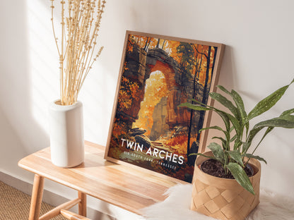 A framed Twin Arches poster rests on a wooden bench beside a white vase and a potted plant, illuminated by natural light.