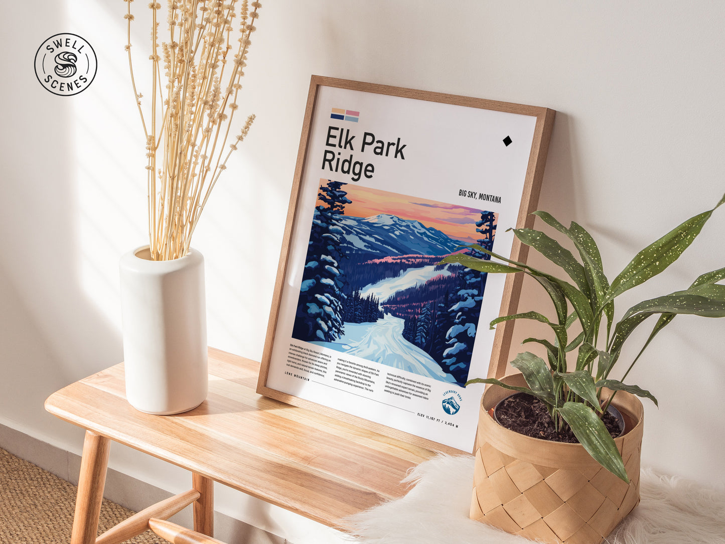 A framed Elk Park Ridge poster rests on a wooden bench, surrounded by a white vase with dried flowers and a potted plant, creating a cozy decor setup.