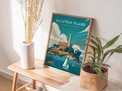 A framed Alcatraz Island poster sits on a wooden bench next to a white vase with dried flowers and a potted green plant.