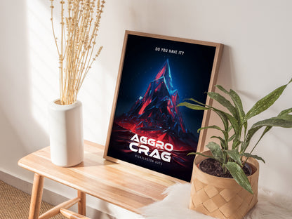 A framed Aggro Crag poster with vibrant colors leans against a wall on a wooden bench, accompanied by a white vase with dried flowers and a potted plant.