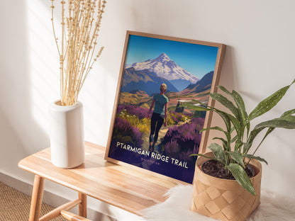 A framed Ptarmigan Ridge Trail poster leans against a wall, surrounded by a white vase with dried flowers and a potted plant on a wooden bench.