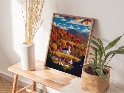 A framed poster of Stowe, Vermont, showcasing a white church steeple surrounded by vibrant fall foliage, rests on a wooden bench beside a vase of dried stems and a potted.