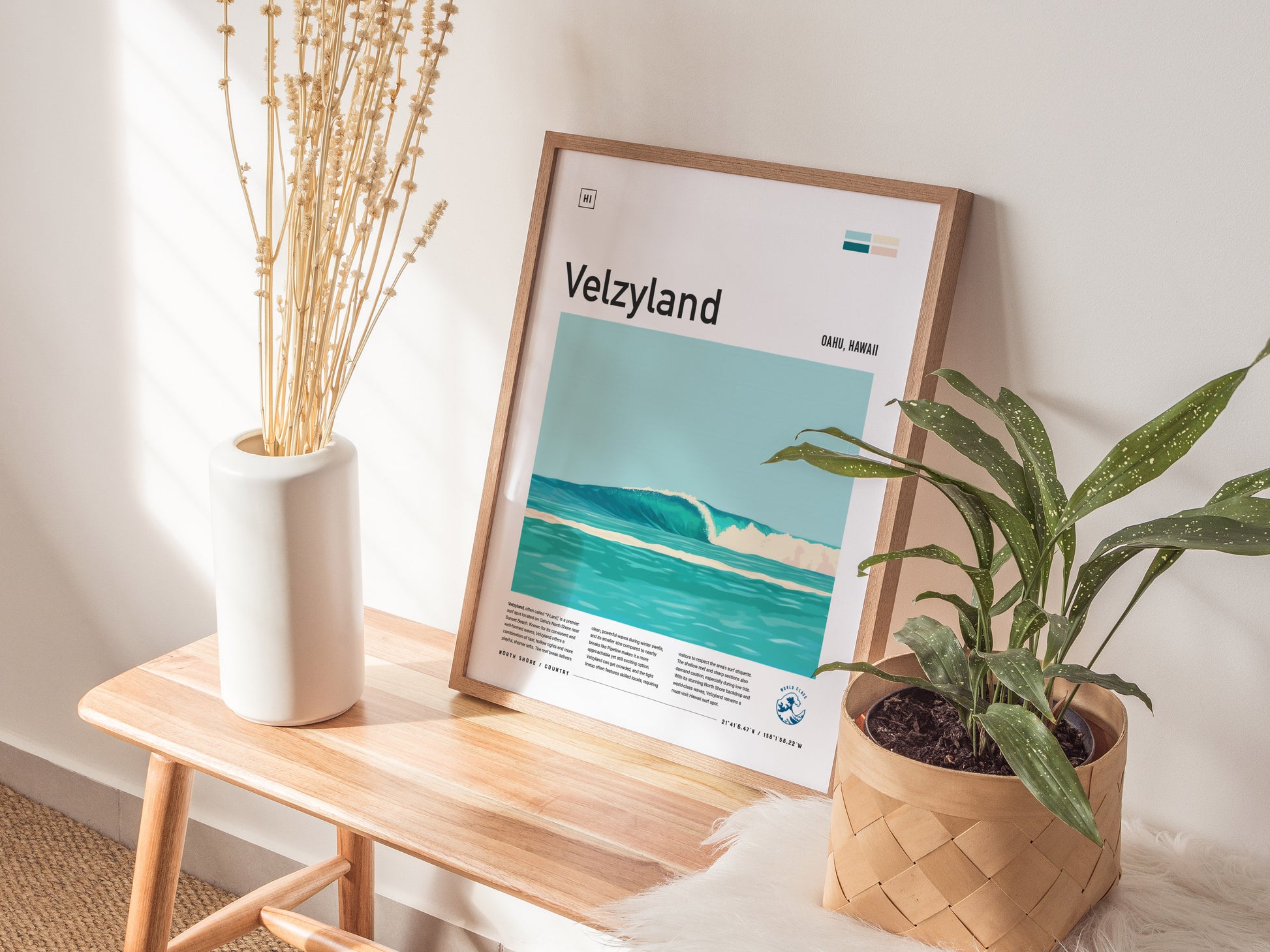 A Velzyland surf poster leans against a wall on a wooden bench, accompanied by a white vase with dried flowers and a potted plant. Sunlight casts soft shadows.