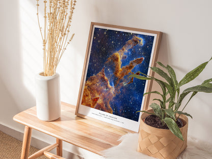Natural wood framed Pillars of Creation print leaning on a shelf with soft ambient lighting