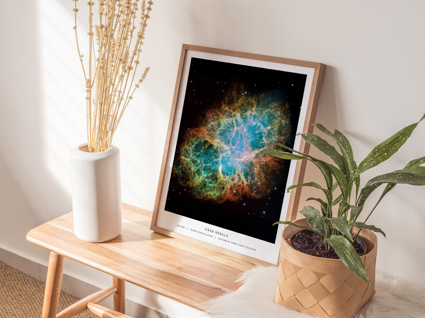 Framed space-themed poster on a wooden side table with plants and a vase.