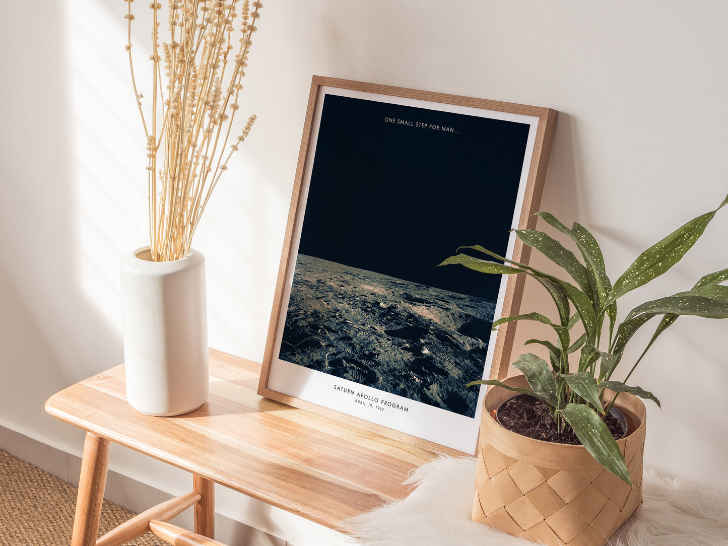 Natural wood framed Apollo 12 NASA lunar surface print leaning on a shelf with plants and ceramics