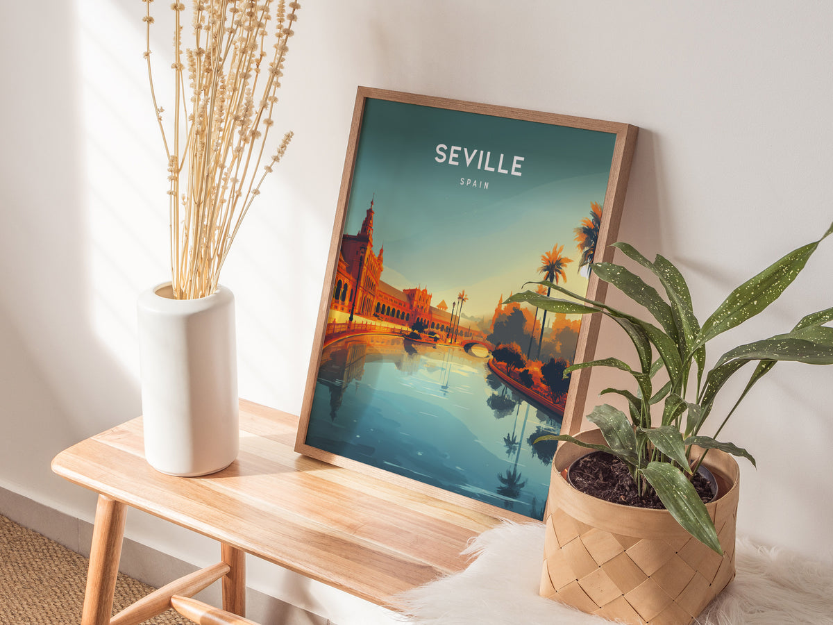 A framed poster of Seville, Spain, featuring vibrant colors and a serene scene of palm trees, historic architecture, and a reflective waterway. The artwork is positioned on a wooden table alongside a potted plant and a decorative vase.