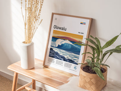 A framed Olowalu Maui surf poster leans against a wall on a wooden bench, accompanied by a white vase with dried flowers and a potted plant.
