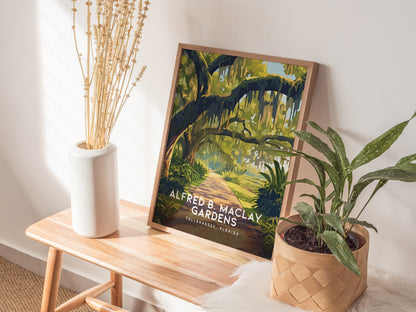 A framed poster of Alfred B. Maclay Gardens is displayed on a wooden bench, accompanied by a white vase with dried flowers and a potted plant in a basket.