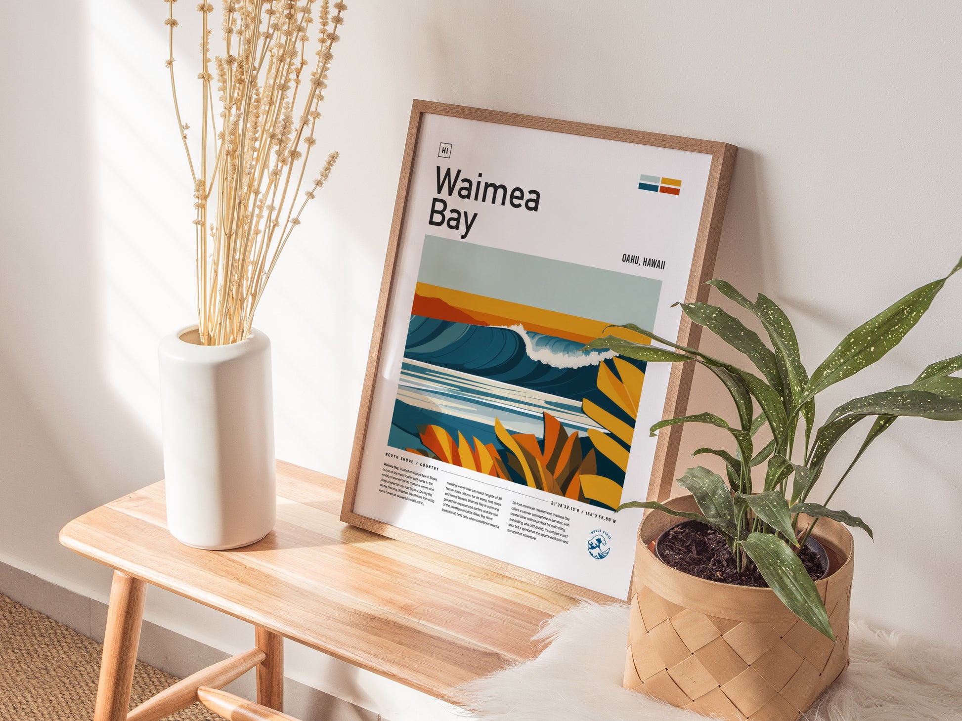 A framed Waimea Bay poster with vibrant wave art is positioned on a wooden bench beside a vase of dried flowers and a potted plant, creating a cozy decor setting.