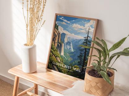 A framed Clouds Rest Trail poster rests on a wooden bench, surrounded by a white vase with tall dried stems and a potted green plant in a woven basket.