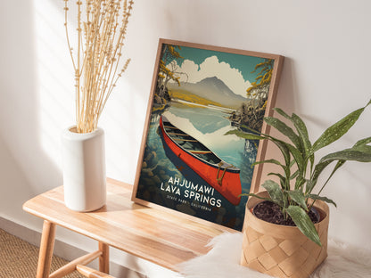 A framed Ahjumawi Lava Springs poster rests on a wooden bench, surrounded by a white vase with dried flowers and a potted green plant. Sunlight casts soft shadows.