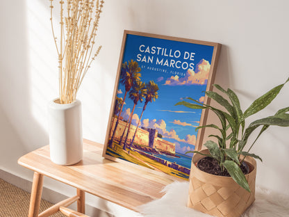 A framed Castillo de San Marcos poster leans on a wall, placed on a wooden bench beside a white vase with dried flowers and a potted plant.