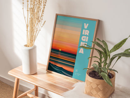 A framed Virginia poster with vibrant sunset colors and bold text rests on a wooden bench, accompanied by a white vase with dried flowers and a potted plant.