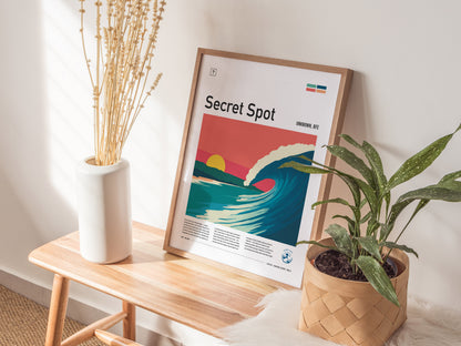 A framed poster titled Secret Spot showcases a vibrant illustration of a wave rolling under a pink and orange sky, accompanied by text indicating the location as Unknown, BFE.