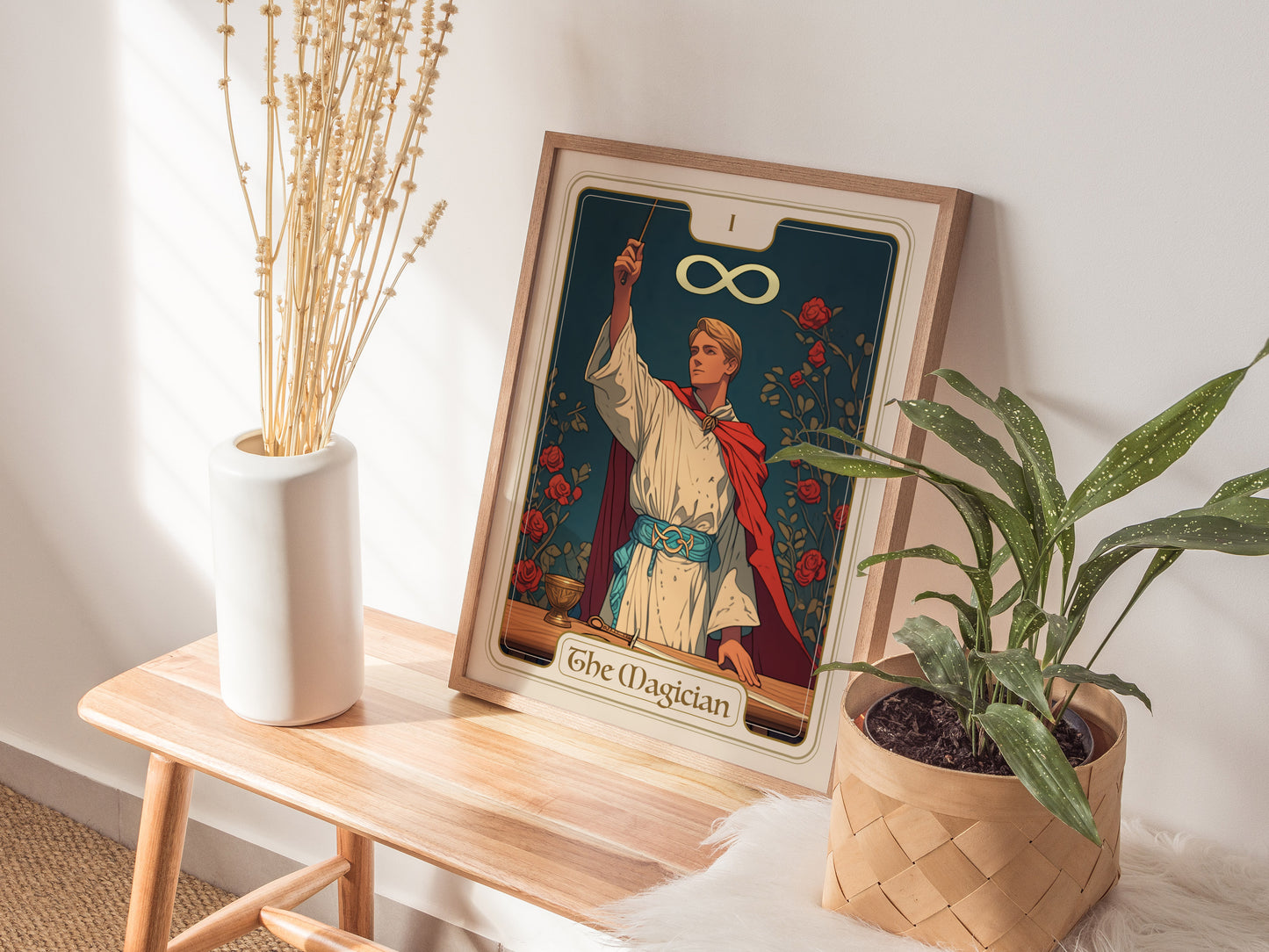 A wooden table displays a framed The Magician tarot card poster featuring a robed figure with a wand, infinity symbol, and floral background, alongside decorative plants and a vase.