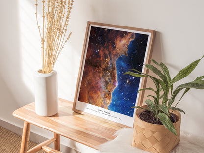 Natural wood framed Carina Nebula print leaning on a shelf with soft ambient lighting