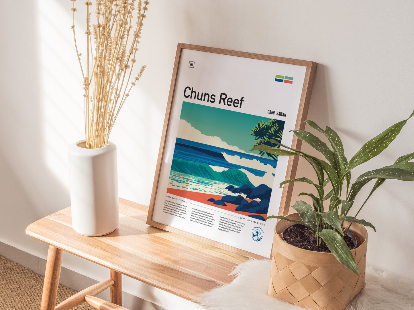 A framed poster titled Chuns Reef is displayed on a wooden table, featuring an illustrated scene of rolling waves and tropical foliage, capturing the essence of Oahus surf culture.