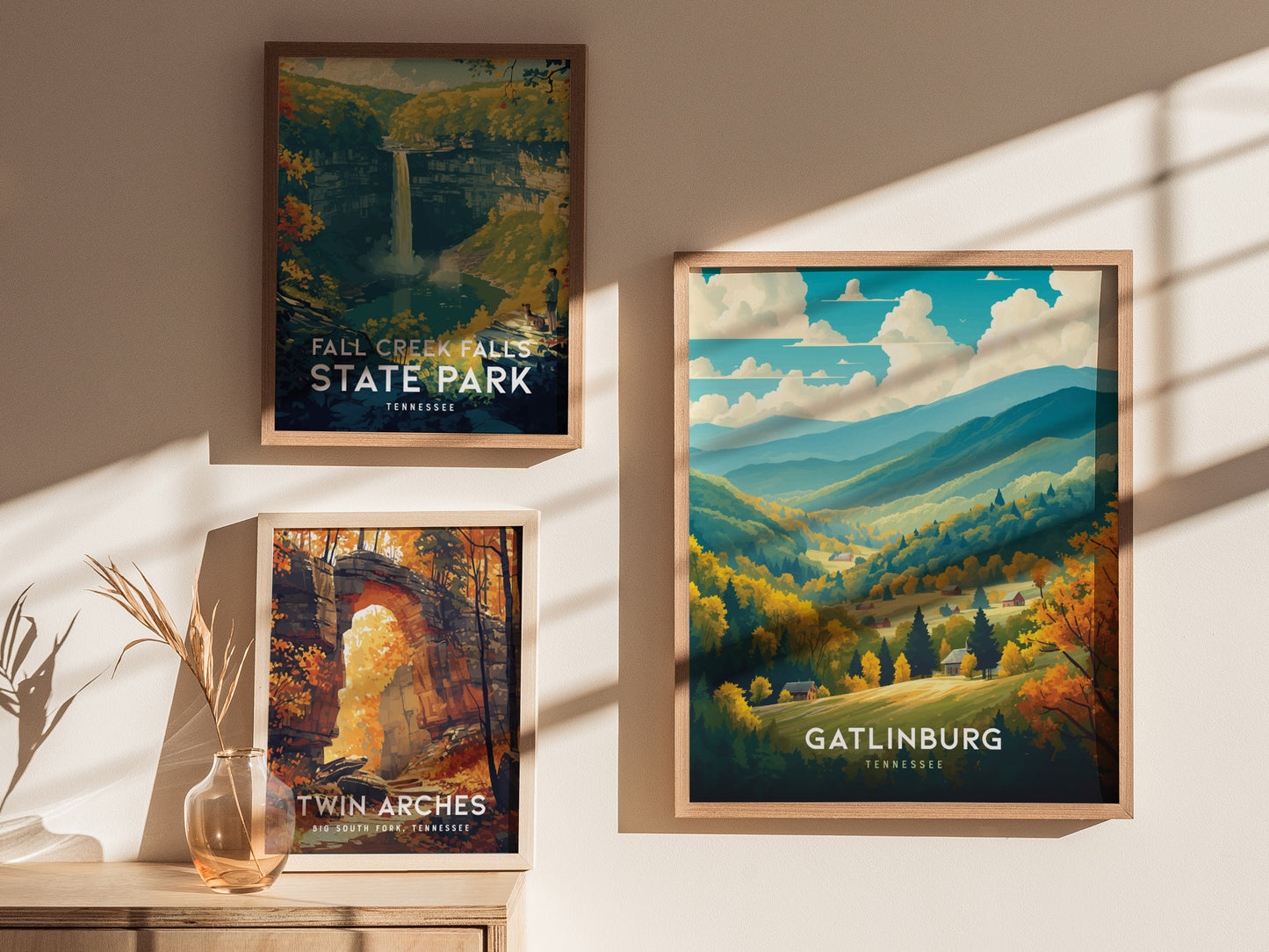 Three framed posters on a wall depict scenic landscapes: Fall Creek Falls State Park, Twin Arches, and Gatlinburg, featuring vibrant autumn colors and mountainous views under sunlight.