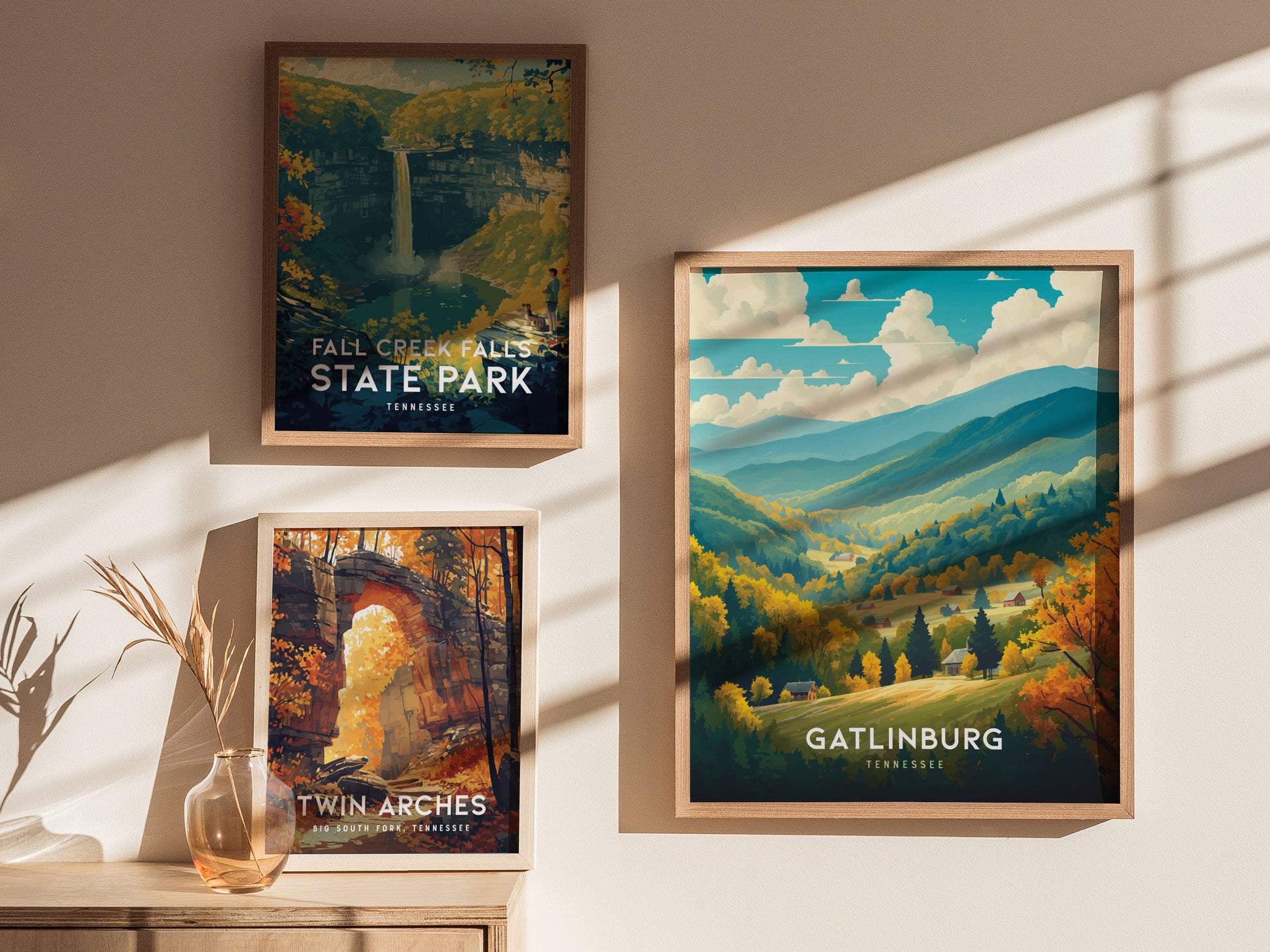 Three framed posters on a wall depict scenic landscapes: Fall Creek Falls State Park, Twin Arches, and Gatlinburg, featuring vibrant autumn colors and mountainous views under sunlight.