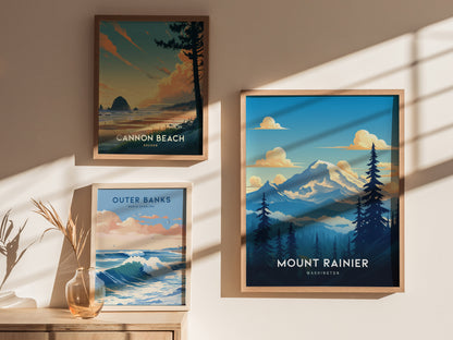 Three framed posters on a sunlit wall depict Cannon Beach, Outer Banks, and Mount Rainier. The scenes include a beach, ocean waves, and a snow-capped mountain with trees.