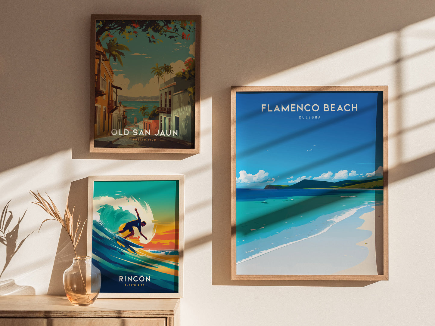 Three framed posters are displayed on a sunlit wall, featuring vibrant scenes of Old San Juan, Rincon, and Flamenco Beach in Puerto Rico, with shadows cast from window panes.