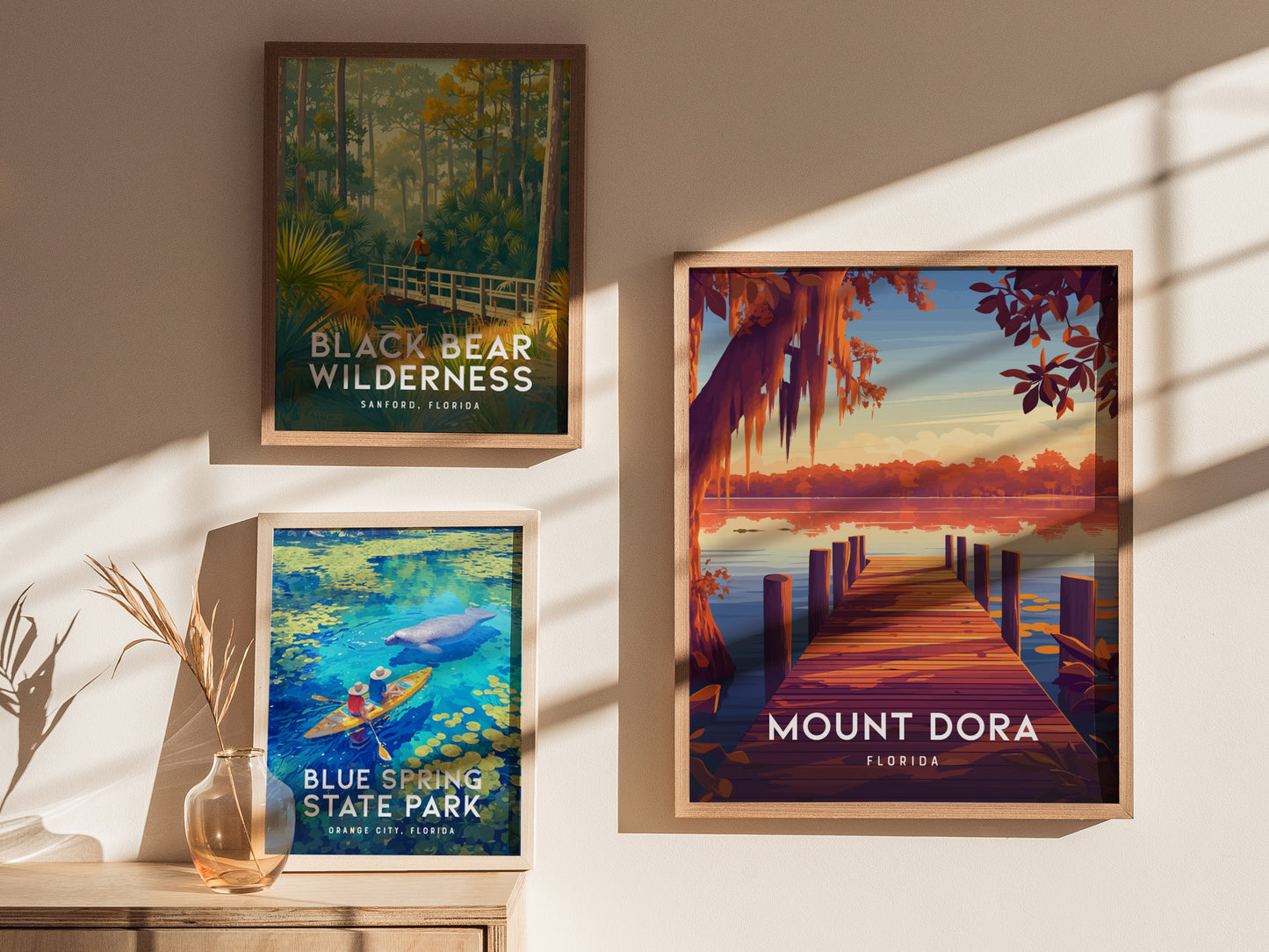 Three framed posters on a wall display scenic Florida locations: Black Bear Wilderness, Blue Spring State Park with a kayaker, and Mount Dora featuring a sunset over a lake.