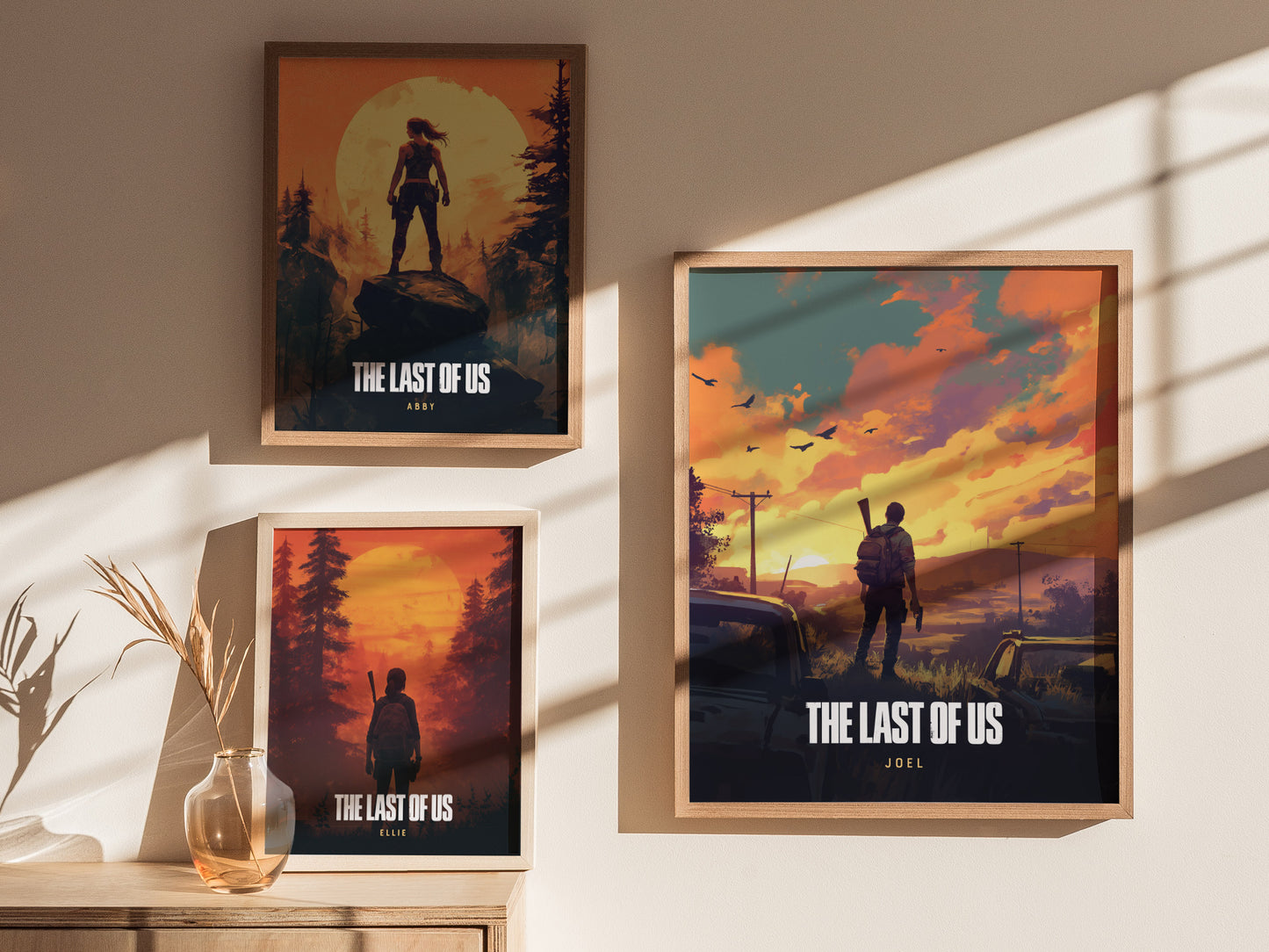 Three framed posters from The Last of Us are displayed on a wall. Each features a character silhouette against dramatic landscapes, with sunlight casting shadows around them.