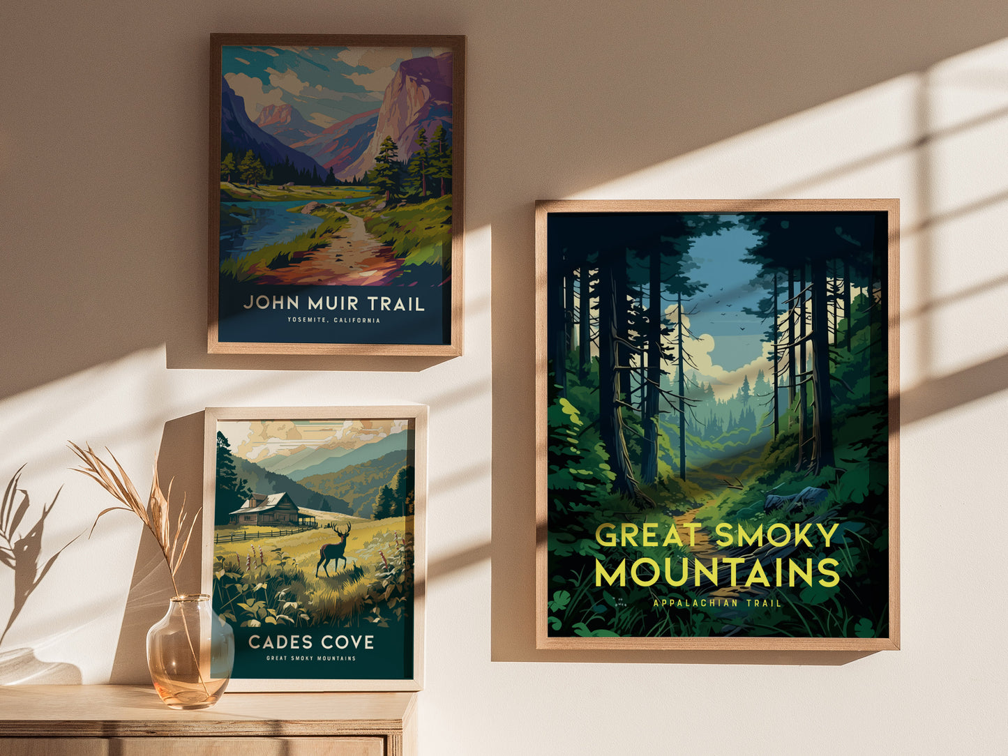 Three framed posters are displayed on a wall, depicting nature scenes from John Muir Trail, Cades Cove, and the Great Smoky Mountains under soft sunlight.