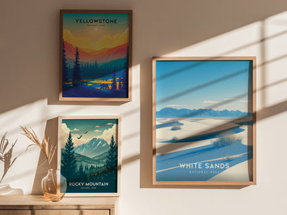 Three framed posters on a wall depict White Sands, Yellowstone, and Rocky Mountain National Parks, with natural scenery and vibrant colors. A vase with dried plants sits nearby.