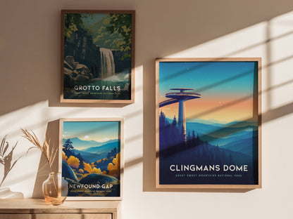 Three framed posters are displayed on a sunlit wall. The top left features Grotto Falls with a waterfall scene, the bottom left shows Newfound Gap with autumn foliage, and the right poster depicts Clingmans Dome at sunset with rolling.